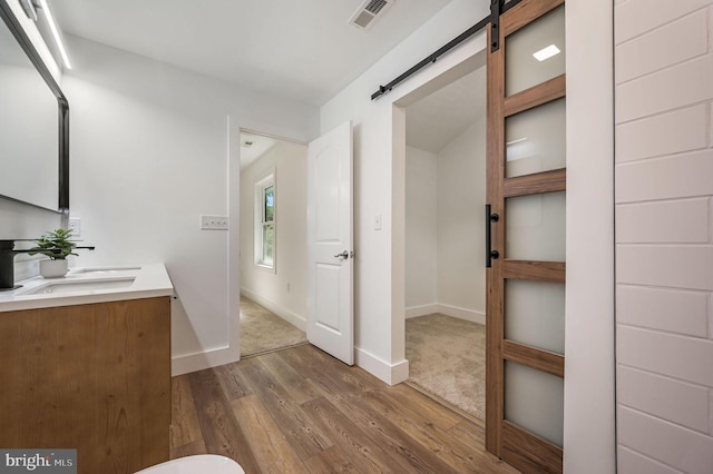 bathroom with baseboards, a sink, visible vents, and wood finished floors