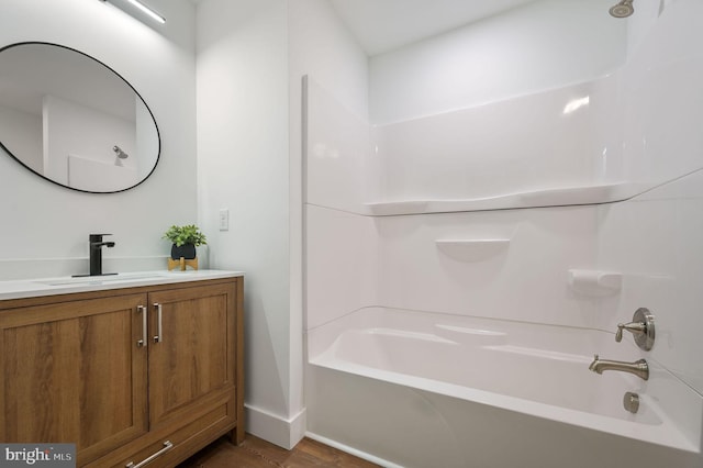 bathroom featuring vanity, baseboards, bathing tub / shower combination, and wood finished floors
