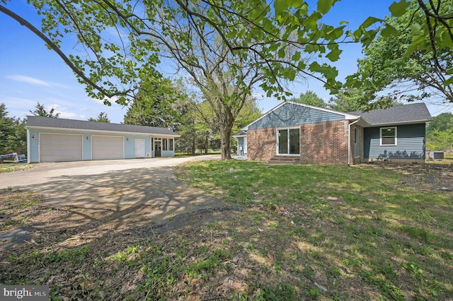 view of front of house with a front lawn, brick siding, an attached garage, central air condition unit, and driveway