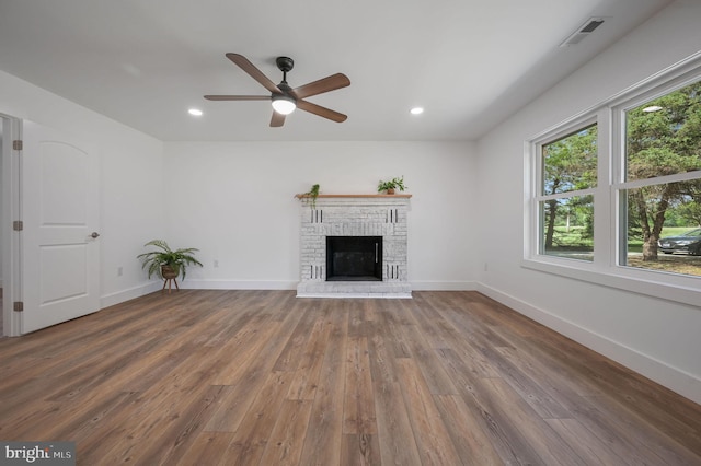 unfurnished living room featuring a ceiling fan, baseboards, visible vents, and wood finished floors