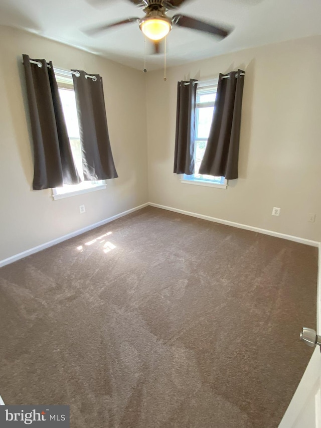 carpeted empty room featuring plenty of natural light, a ceiling fan, and baseboards