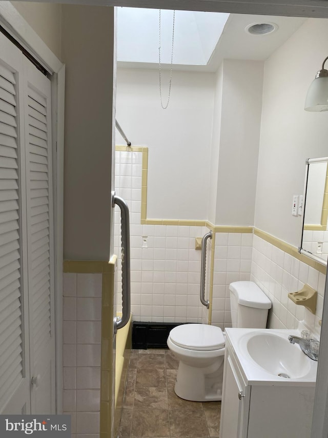 bathroom featuring walk in shower, toilet, tile walls, and a wainscoted wall