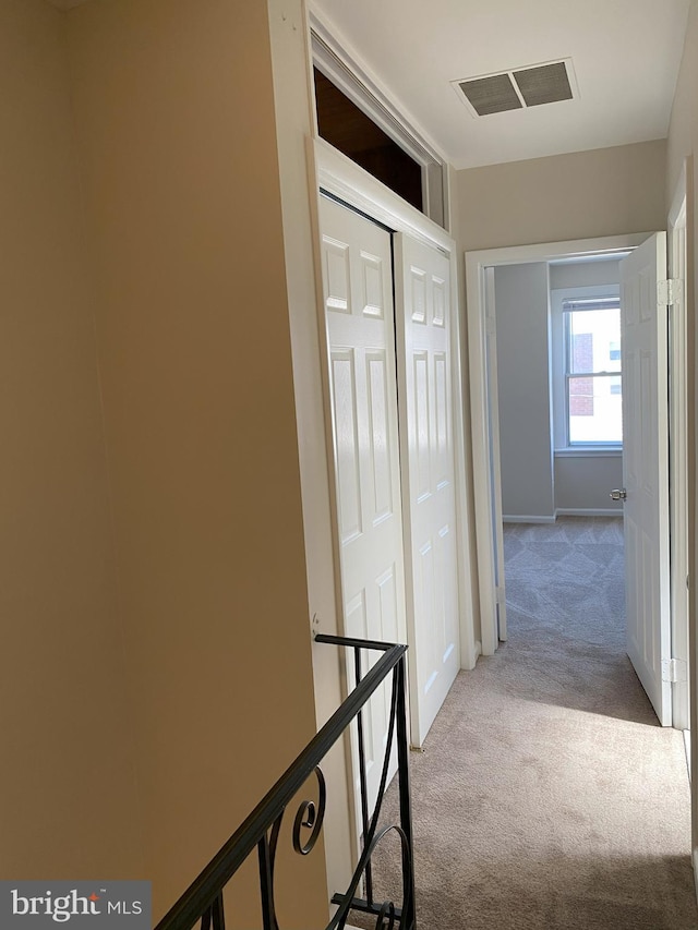 hallway featuring visible vents and light carpet