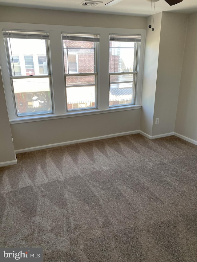 carpeted empty room featuring baseboards, ceiling fan, and visible vents