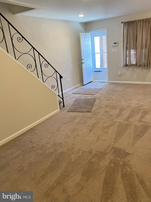 foyer entrance with carpet floors, baseboards, and stairway