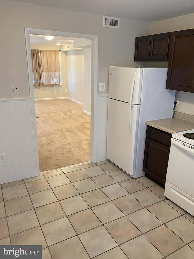 kitchen featuring dark brown cabinets, visible vents, white electric stove, and light carpet