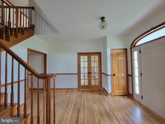 foyer entrance featuring plenty of natural light, french doors, stairway, and light wood-style floors