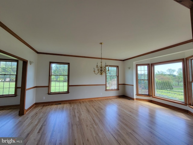 empty room featuring baseboards, ornamental molding, wood finished floors, and a chandelier