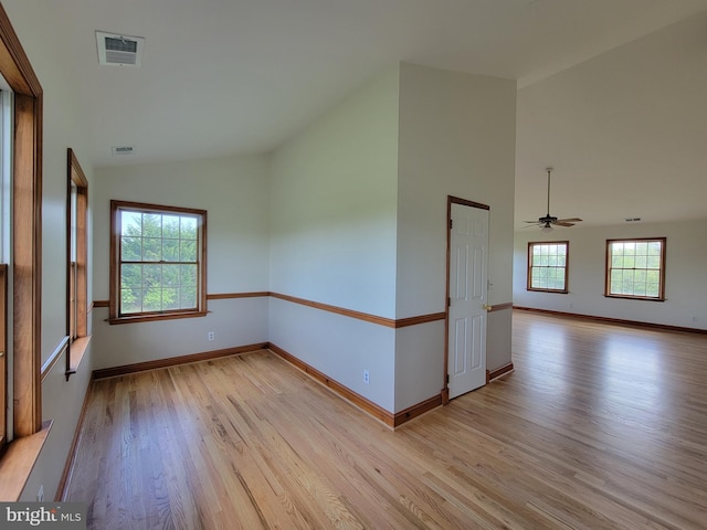 spare room with ceiling fan, light wood-style floors, baseboards, lofted ceiling, and visible vents