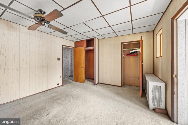 unfurnished bedroom featuring carpet flooring and wood walls
