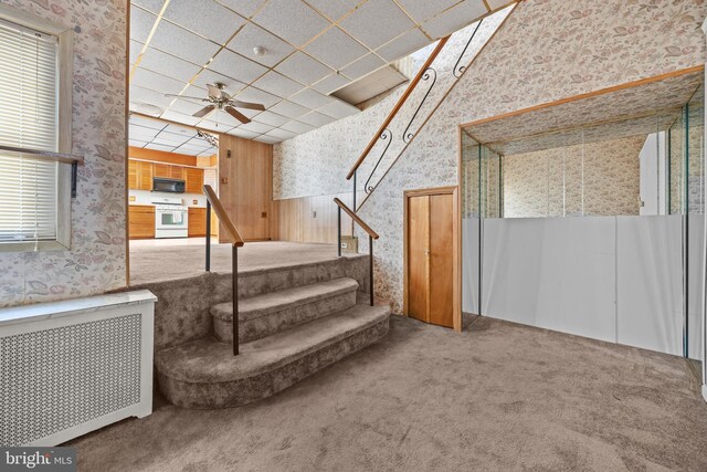 basement with radiator, ceiling fan, wallpapered walls, and stairs