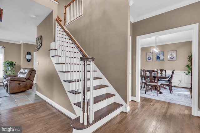 stairs featuring wood finished floors, baseboards, and ornamental molding