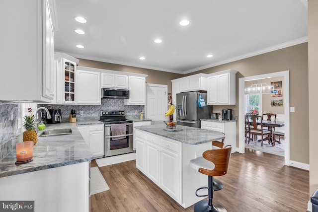 kitchen featuring ornamental molding, a center island, appliances with stainless steel finishes, and a sink