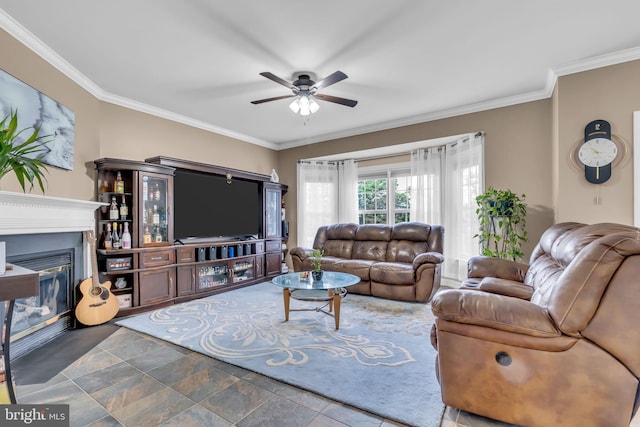 living room with crown molding, a ceiling fan, and a glass covered fireplace