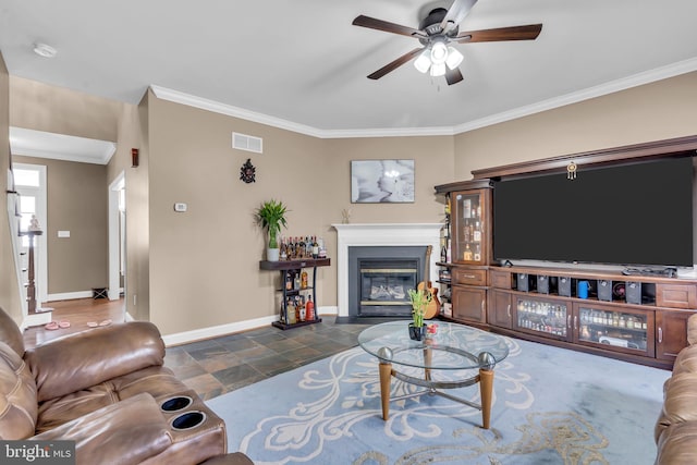living room with ornamental molding, visible vents, ceiling fan, baseboards, and a fireplace with flush hearth