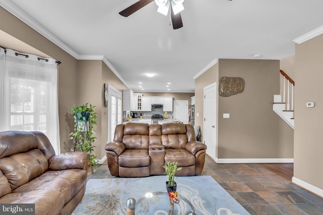 living area featuring stairs, ornamental molding, ceiling fan, stone finish flooring, and baseboards