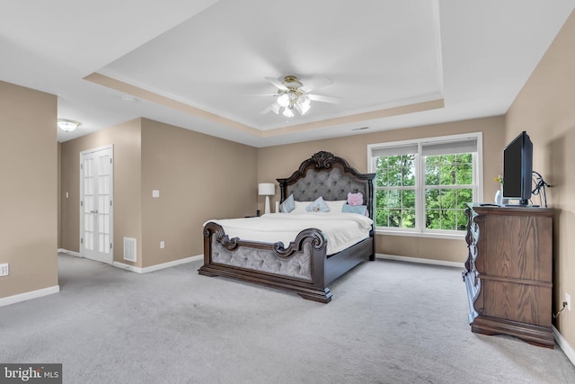 bedroom featuring baseboards, carpet flooring, a tray ceiling, and visible vents