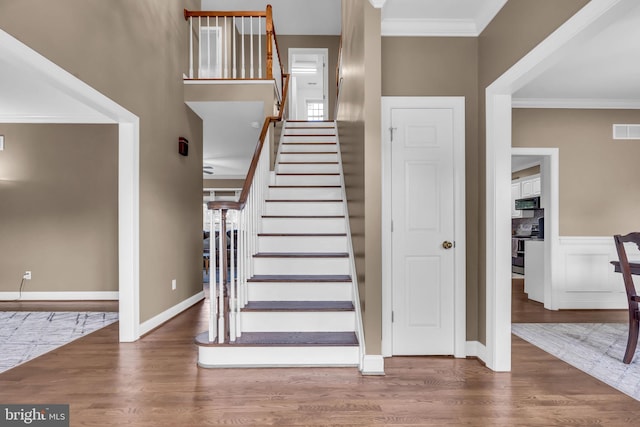 staircase featuring visible vents, crown molding, and wood finished floors