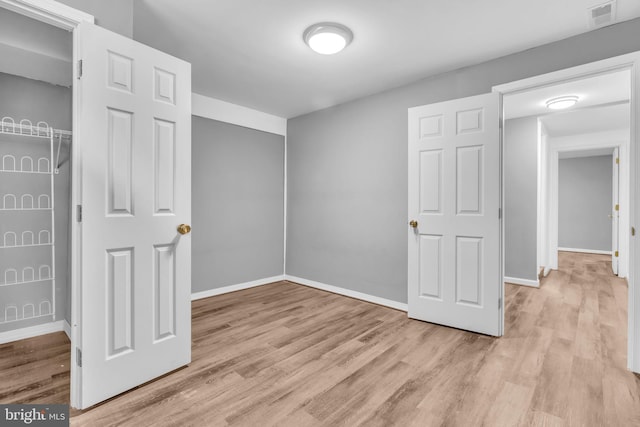 unfurnished bedroom with visible vents, light wood-style flooring, and baseboards
