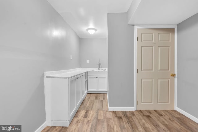 bar with a sink, light wood-style flooring, and baseboards