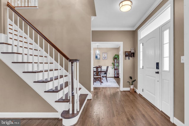 foyer entrance with crown molding, stairway, wood finished floors, and baseboards