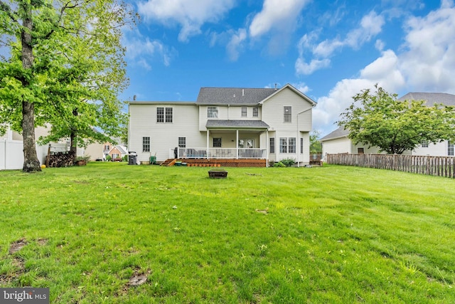 rear view of property featuring a yard, a deck, and a fenced backyard