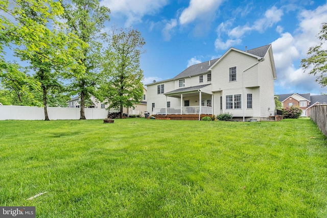 rear view of house featuring a deck, a lawn, and a fenced backyard