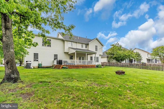 rear view of house with an outdoor fire pit, a yard, a wooden deck, and a fenced backyard