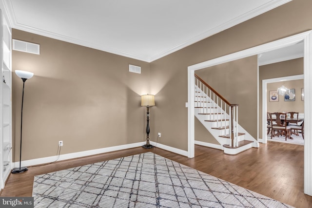 interior space with visible vents, wood finished floors, ornamental molding, and stairway