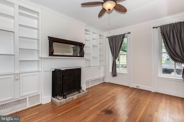 140 Pennsylvania Ave, Westminster, MD 21157 - unfurnished living room with built in shelves, light wood-style floors, ceiling fan, a fireplace with raised hearth, and ornamental molding