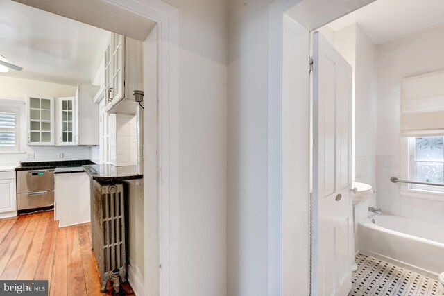 140 Pennsylvania Ave, Westminster, MD 21157 - kitchen featuring stainless steel dishwasher, glass insert cabinets, white cabinetry, dark countertops, and radiator