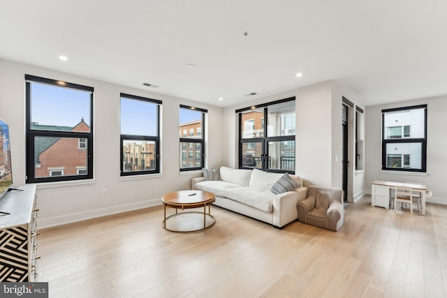 living area with light wood-style floors, baseboards, and recessed lighting