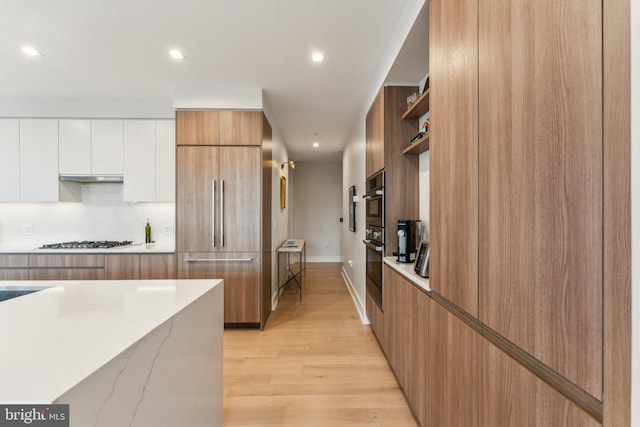 kitchen with modern cabinets, paneled built in refrigerator, open shelves, light wood-style flooring, and recessed lighting