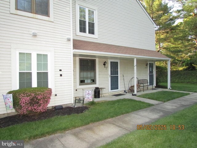 view of property featuring a front lawn, roof with shingles, and covered porch