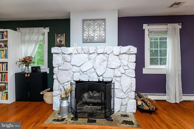 877 Salford Station Rd, Schwenksville, PA 19473 - detailed view of wood finished floors, a stone fireplace, and a baseboard radiator