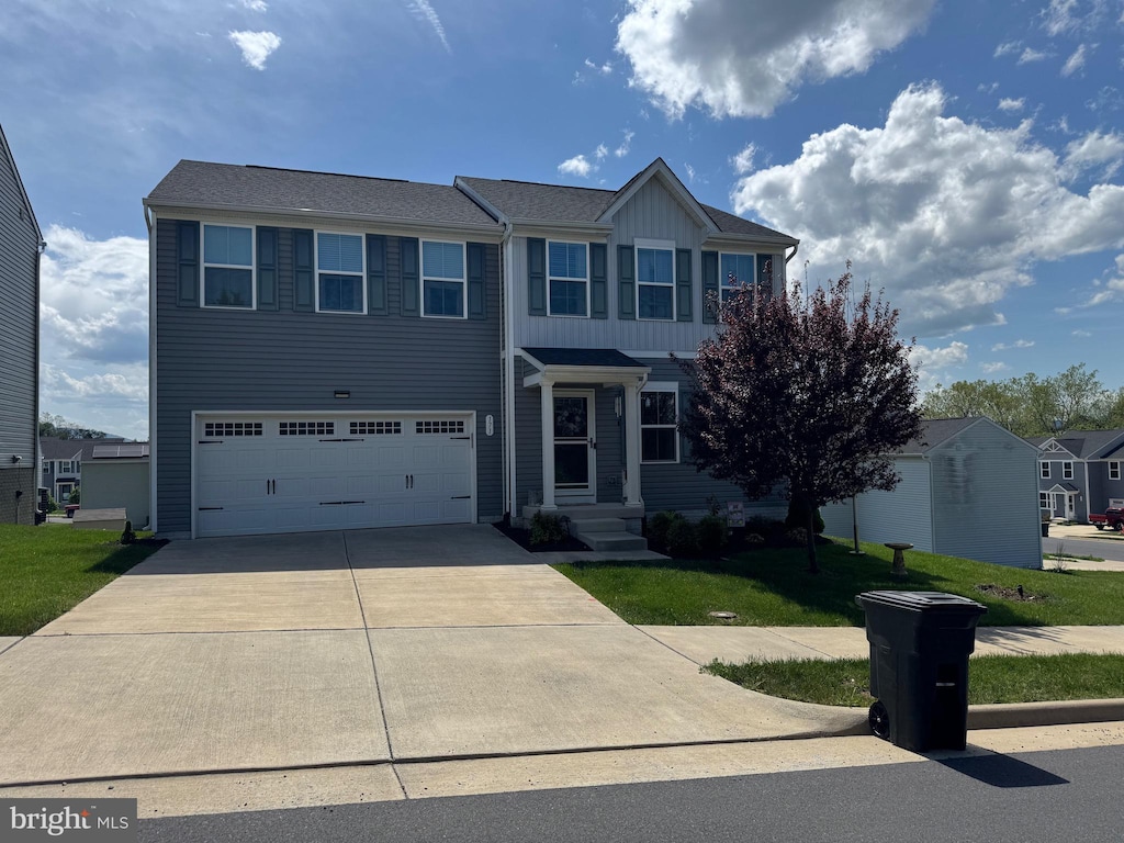 traditional home featuring board and batten siding, an attached garage, concrete driveway, and a front yard