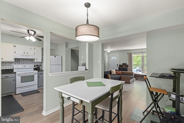 dining area featuring baseboards, ceiling fan, and light wood-type flooring