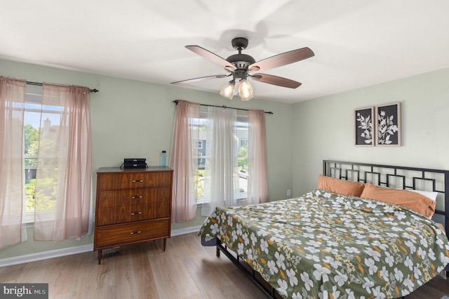 bedroom with baseboards, wood finished floors, and multiple windows