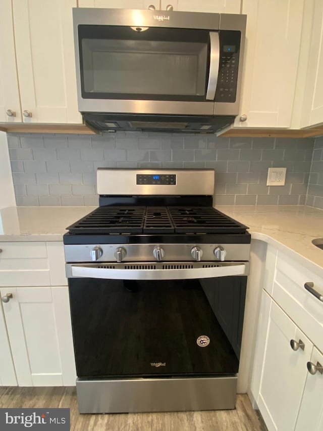 4901 Harbor Beach Blvd Unit P12, Brigantine, NJ 08203 - kitchen with appliances with stainless steel finishes, backsplash, light wood-type flooring, and white cabinetry