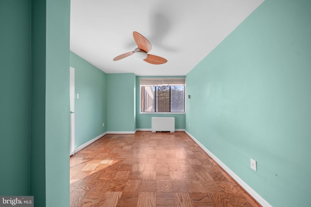 spare room featuring baseboards, radiator, and ceiling fan