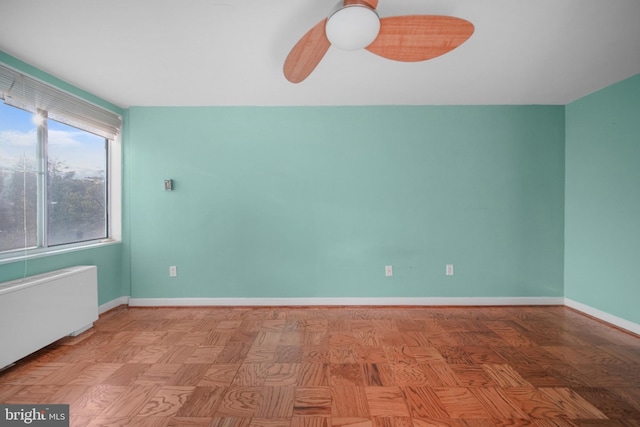 empty room with baseboards, radiator, and ceiling fan