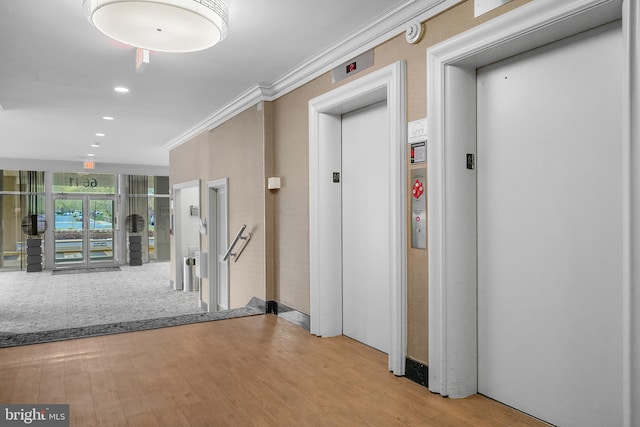 hall with recessed lighting, ornamental molding, wood finished floors, and elevator