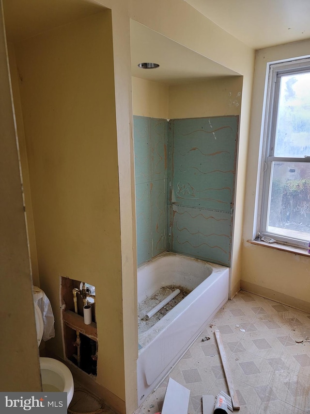 full bathroom with baseboards, a bathtub, and toilet