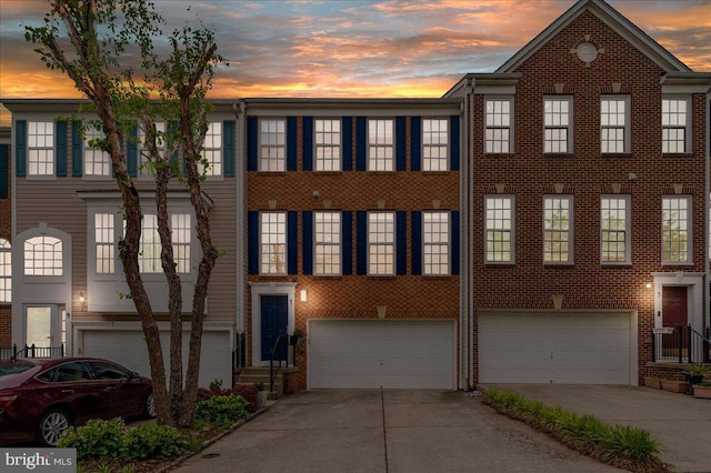 multi unit property with a garage, concrete driveway, and brick siding