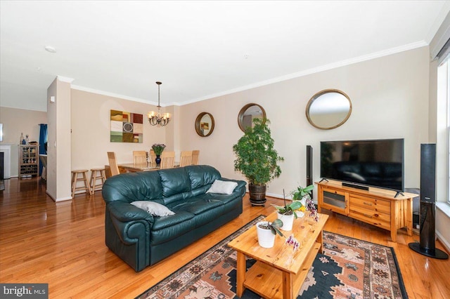 living room with light wood finished floors, ornamental molding, a chandelier, and baseboards