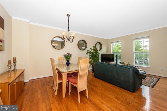 dining room with light wood-style floors, ornamental molding, a chandelier, and baseboards