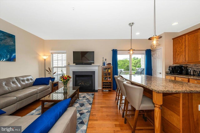 living area featuring light wood-style flooring, recessed lighting, and a glass covered fireplace