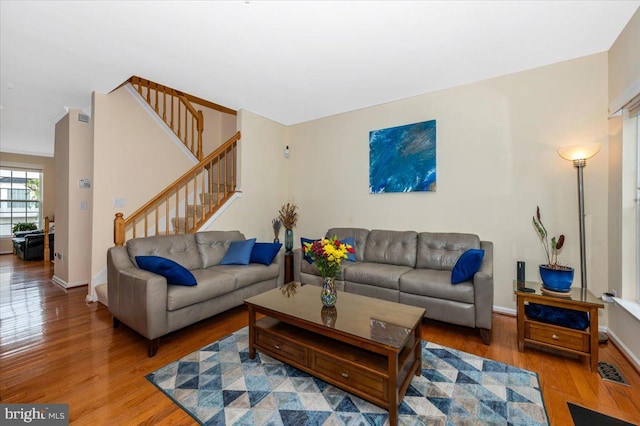 living room featuring wood finished floors, stairs, and baseboards