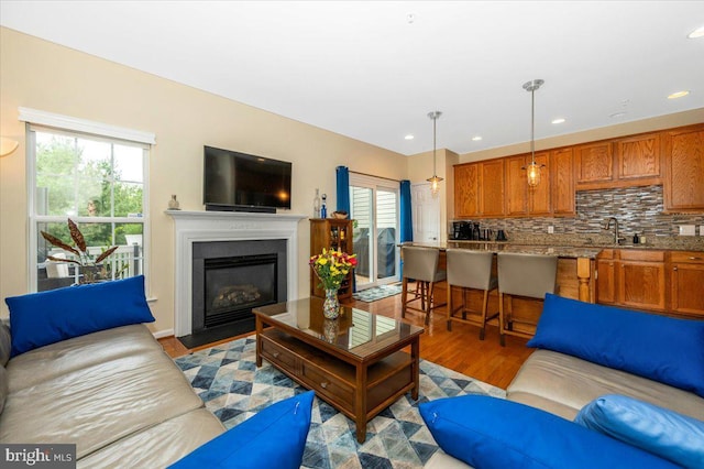 living area featuring wood finished floors, a fireplace with flush hearth, and recessed lighting