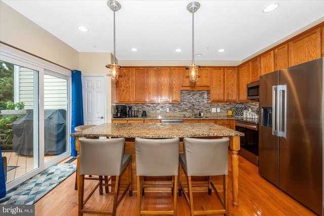 kitchen featuring stainless steel appliances, light wood-style flooring, decorative backsplash, brown cabinets, and recessed lighting